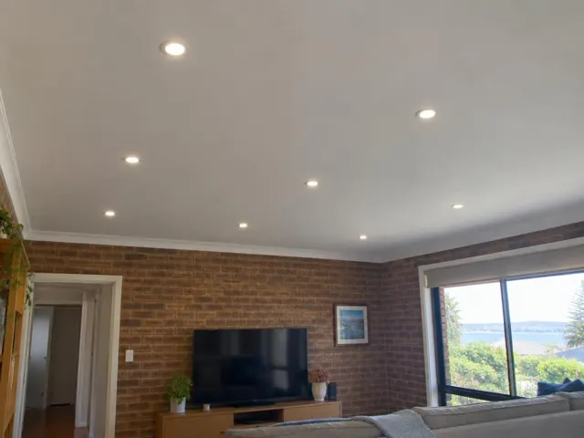 Living room with recessed LED downlights in a brick-walled home interior in Terrigal